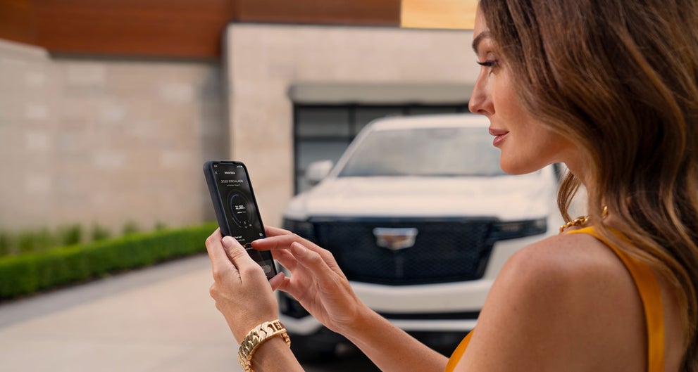 lady checking her mobile with a Cadillac vehicle background | Wilkinson Cadillac in Sanford NC